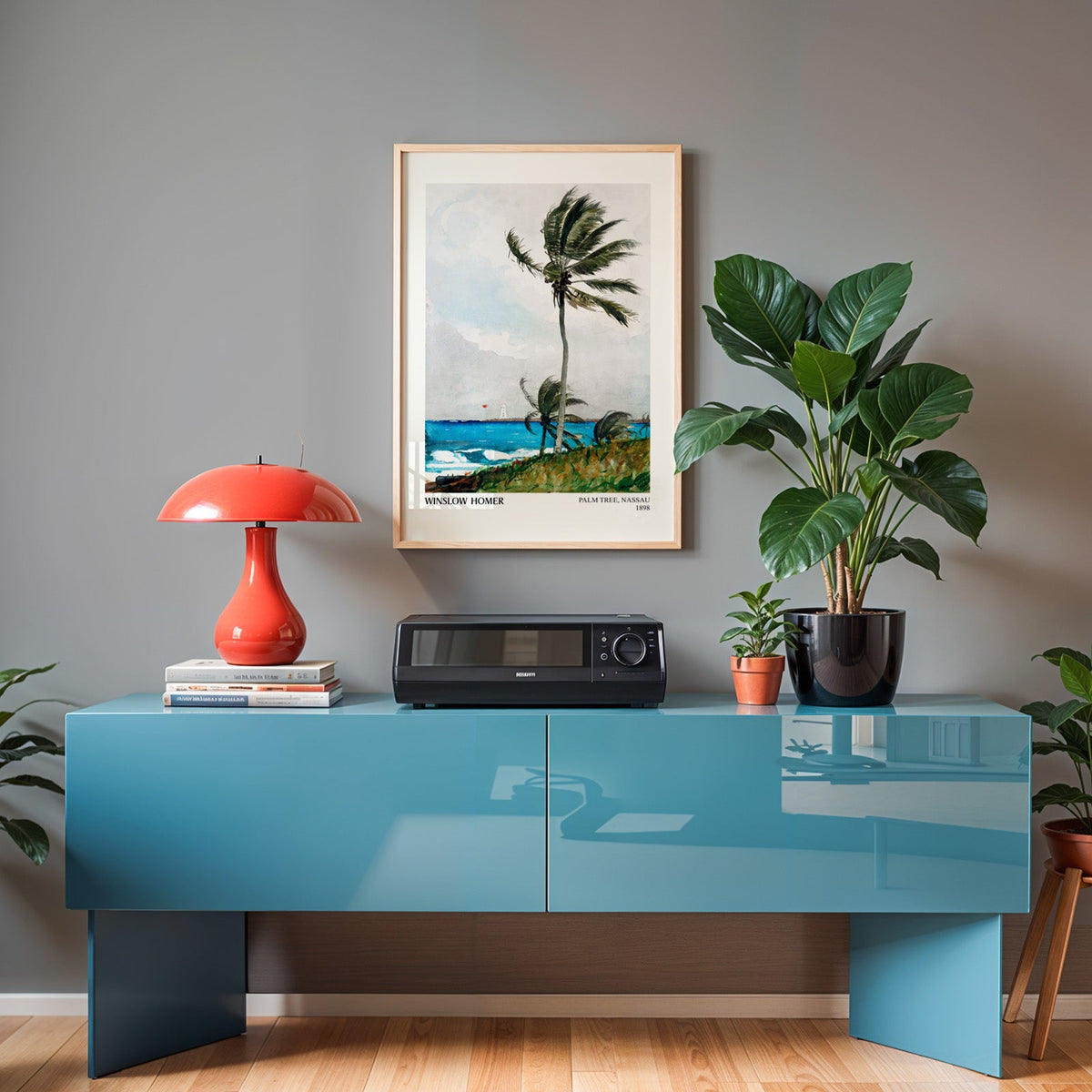 Coastal palm print in an oak frame above a teal sideboard with a red lamp