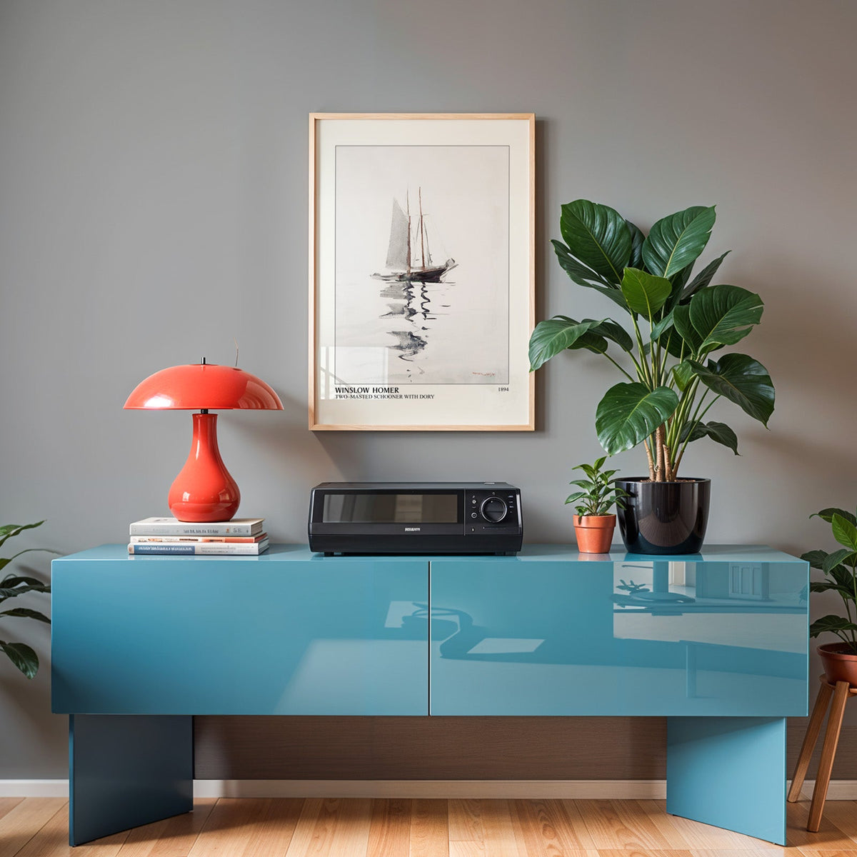 Sailing boat print in an oak frame above a teal sideboard with a red lamp