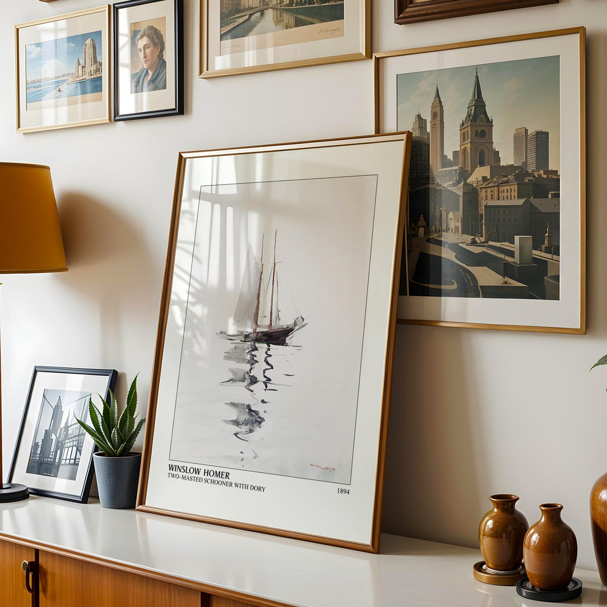 Homer boat print shown in a gold frame leaning on a sideboard in a gallery wall