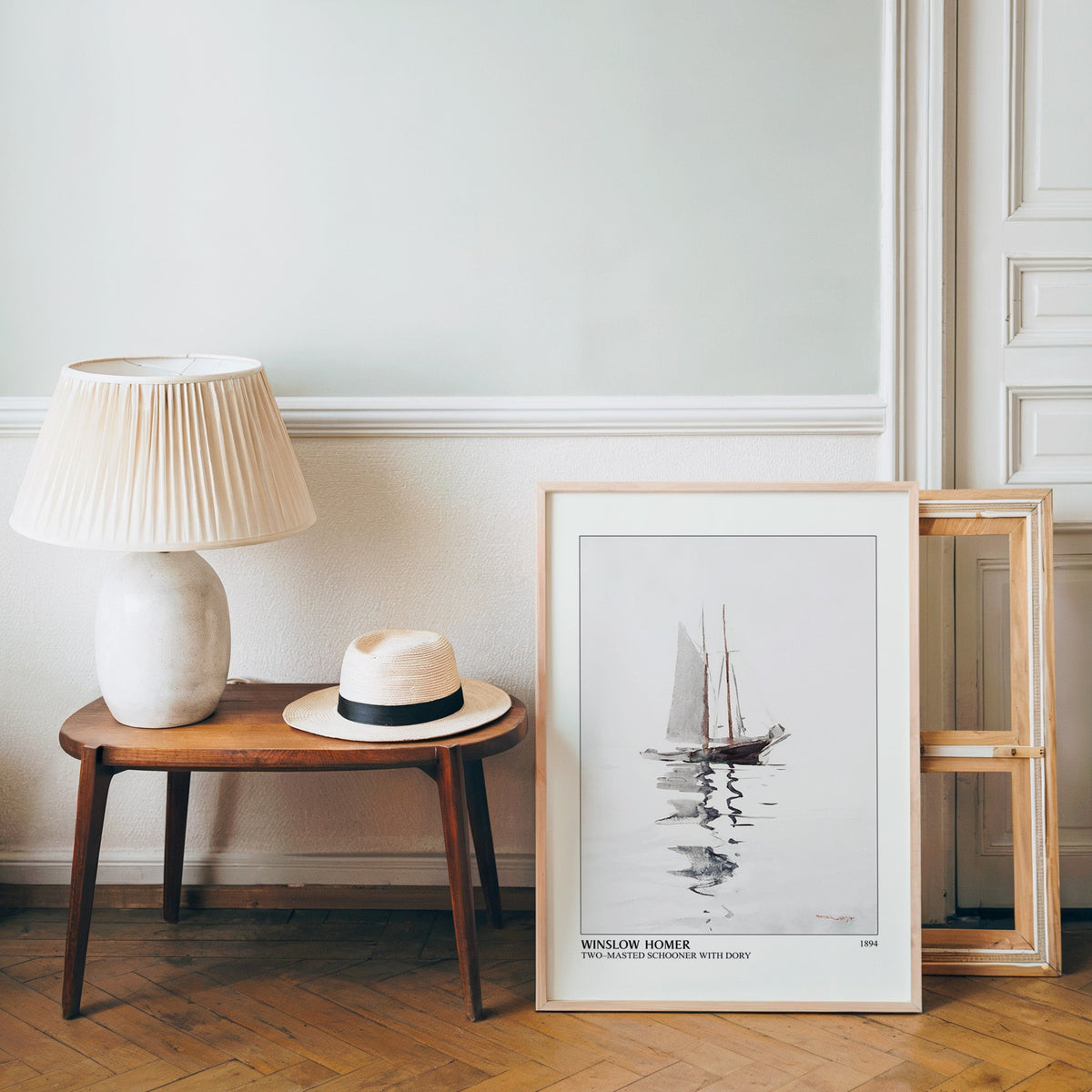 Nautical watercolour poster in a light wood frame leaning by a bench and hat