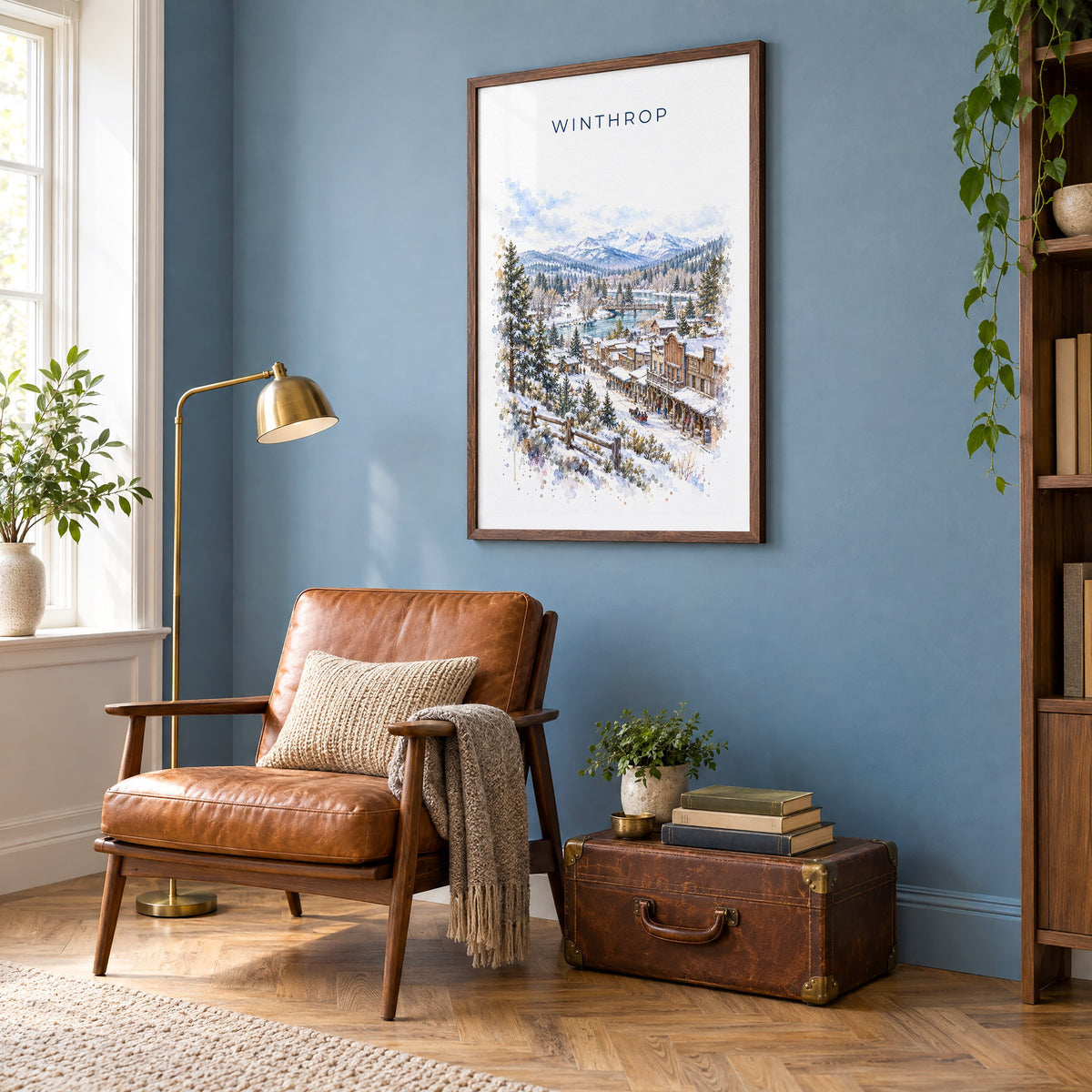Winthrop, Washington watercolor print in a walnut frame on a blue wall above a leather armchair in a reading nook