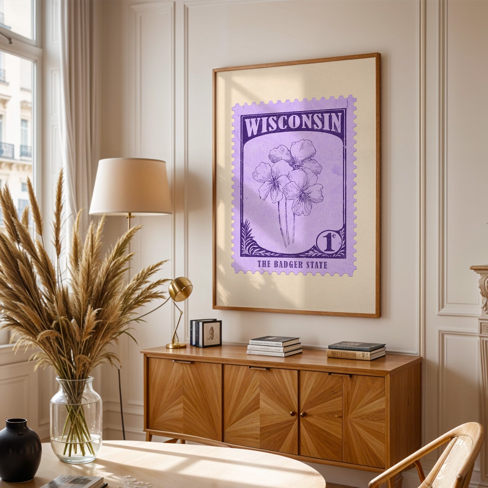 Wisconsin stamp print framed above a wooden sideboard, pampas grass in a glass vase and a floor lamp