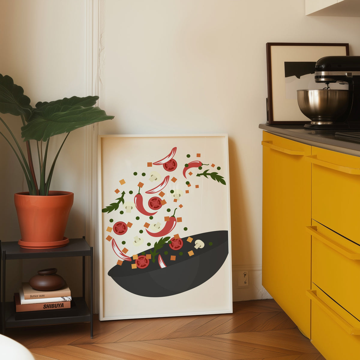 Wok toss print in a white frame leaning on parquet beside a bright yellow kitchen