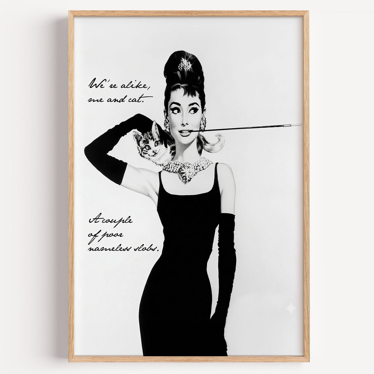 Woman in black dress with kitten and handwritten quote print in a light oak frame on a plain white wall