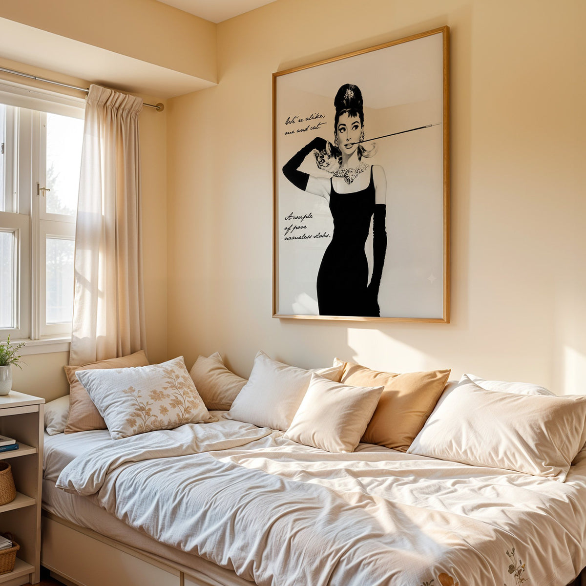 Woman in black dress with kitten and handwritten quote print in an oak frame above a cream daybed in a sunny bedroom