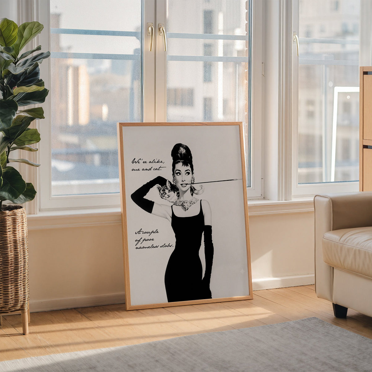 Woman in black dress with kitten and handwritten quote print in an oak frame leaning on the floor beside a fiddle leaf fig