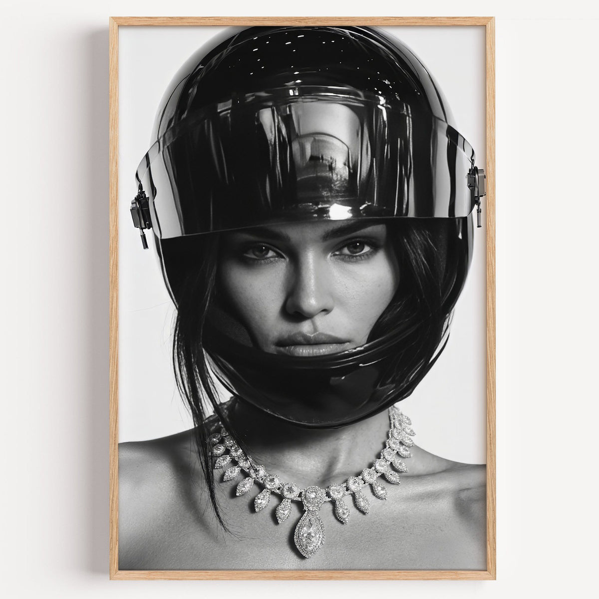 Woman in glossy black helmet and diamond necklace print in a light oak frame on a plain white wall