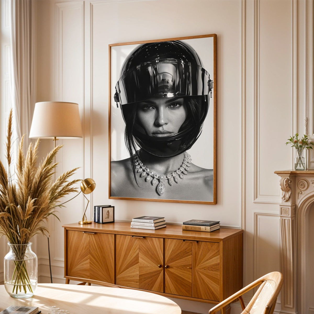 Woman in glossy black helmet and diamond necklace print in an oak frame above a sunburst wood sideboard with pampas grass