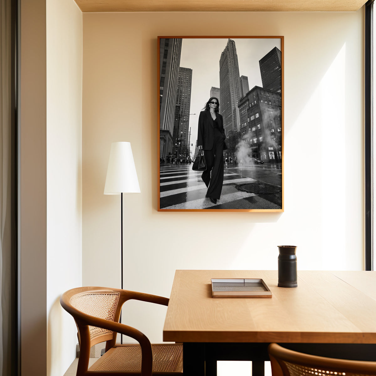 Woman in black suit on New York crosswalk print in an oak frame above a dining table and cane chair