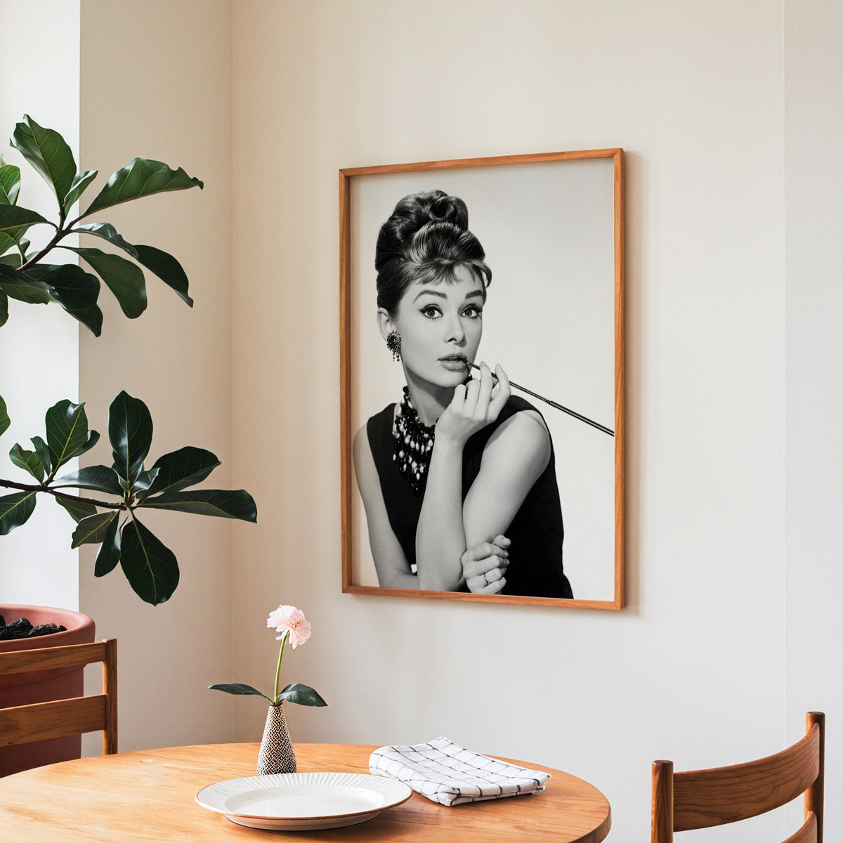 Woman with updo, pearls and long cigarette holder print in a teak frame above a round wooden dining table