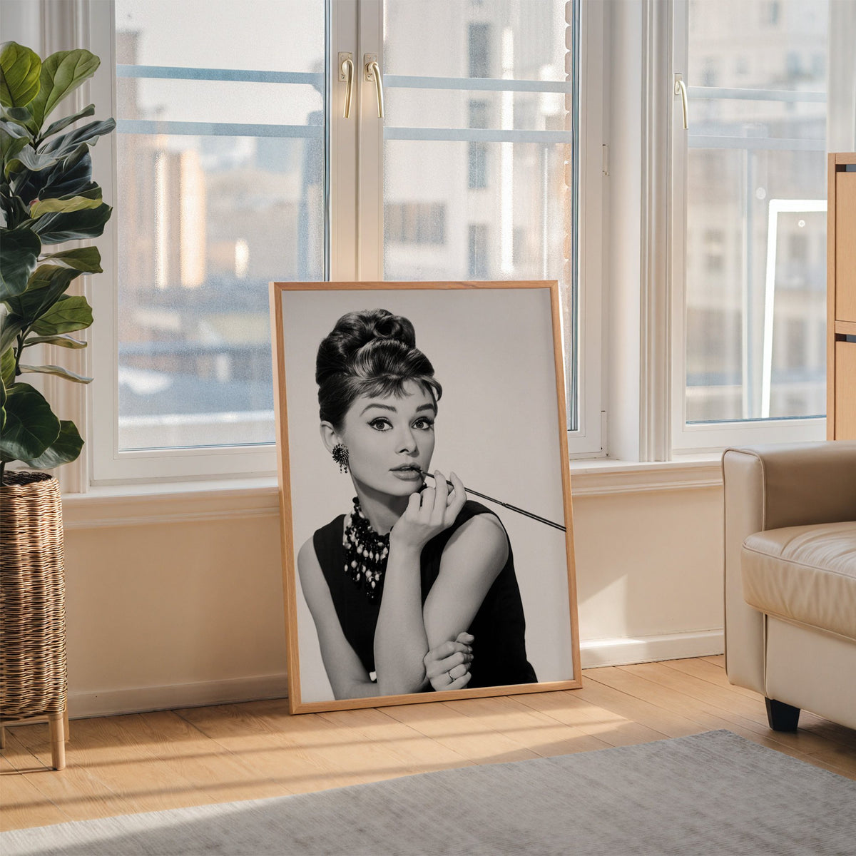Woman with updo, pearls and long cigarette holder print in an oak frame leaning on the floor beside a fiddle leaf fig