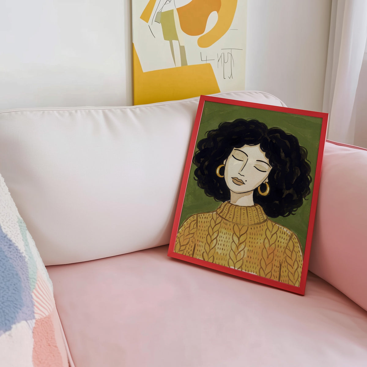 Curly hair woman print shown in a red frame leaning on a blush pink sofa