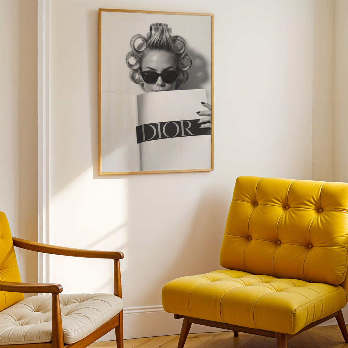 Woman in hair rollers and sunglasses behind magazine print shown in a gold frame above a mustard yellow tufted armchair