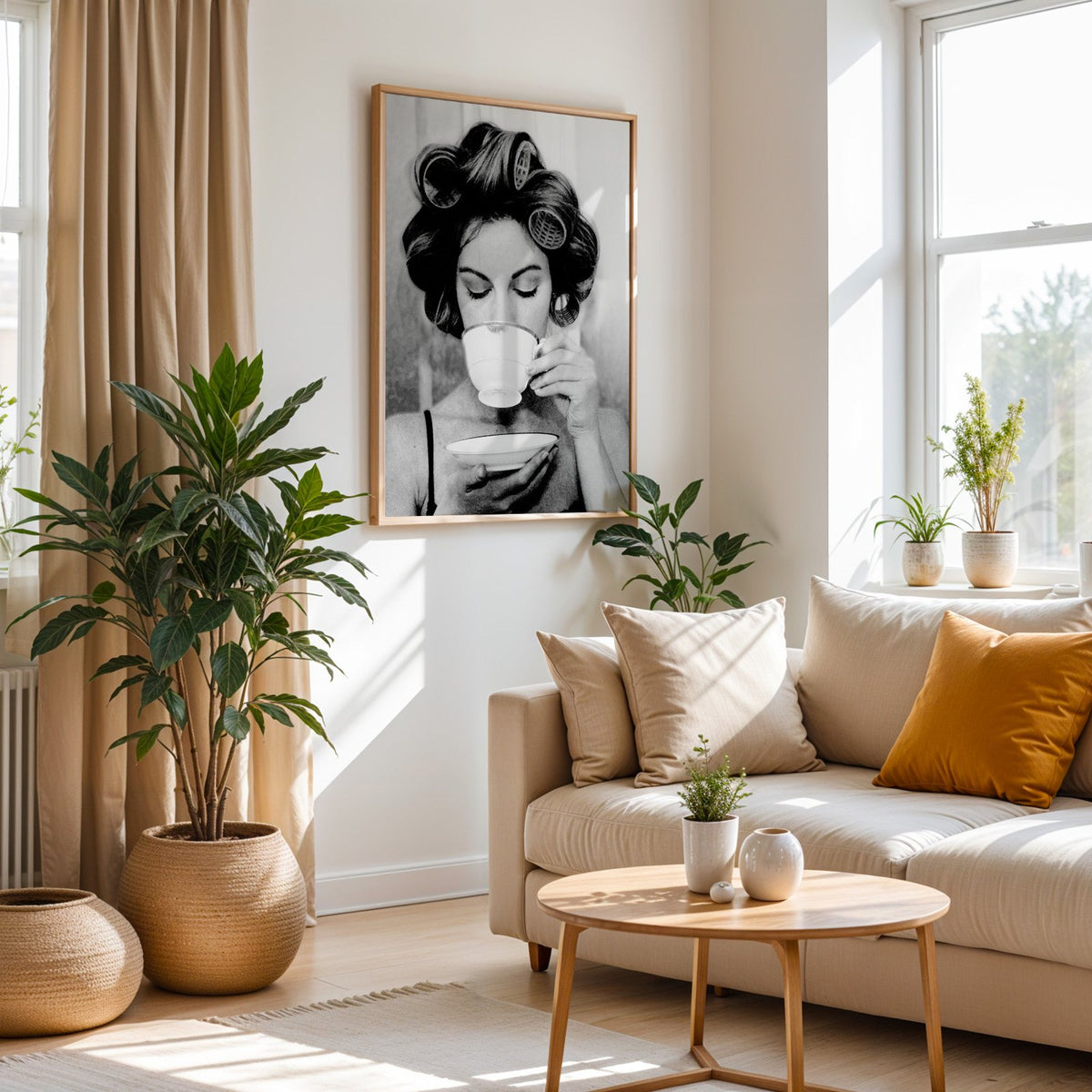 Woman in hair rollers sipping from a teacup print in an oak frame above a cream sofa beside woven planters