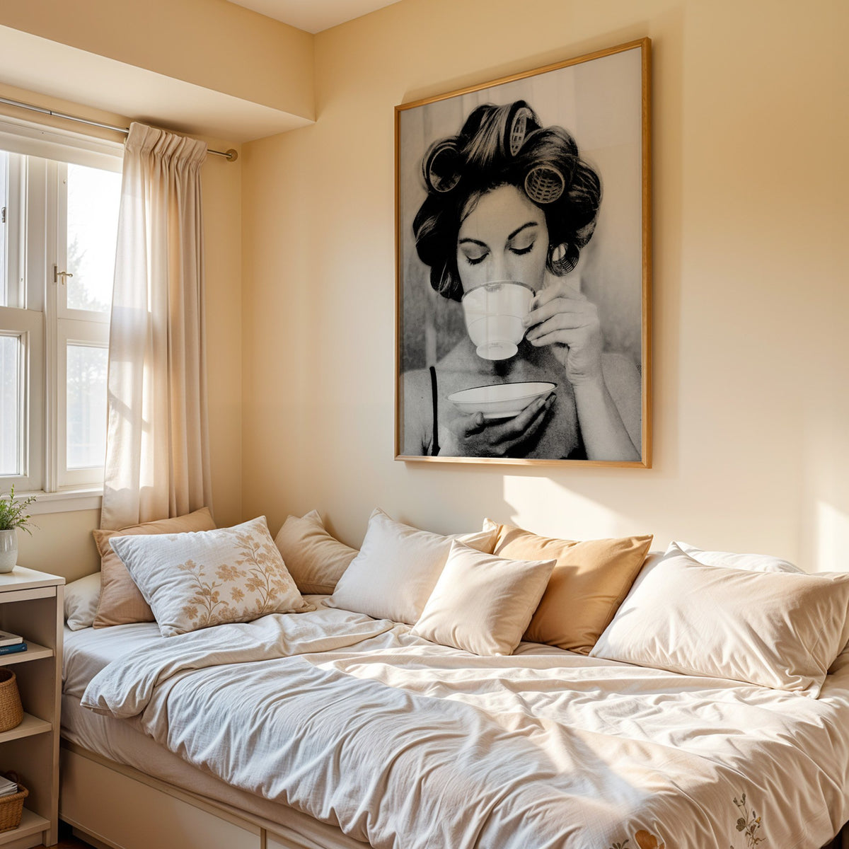 Woman in hair rollers sipping from a teacup print in an oak frame above a cream daybed in a sunny bedroom