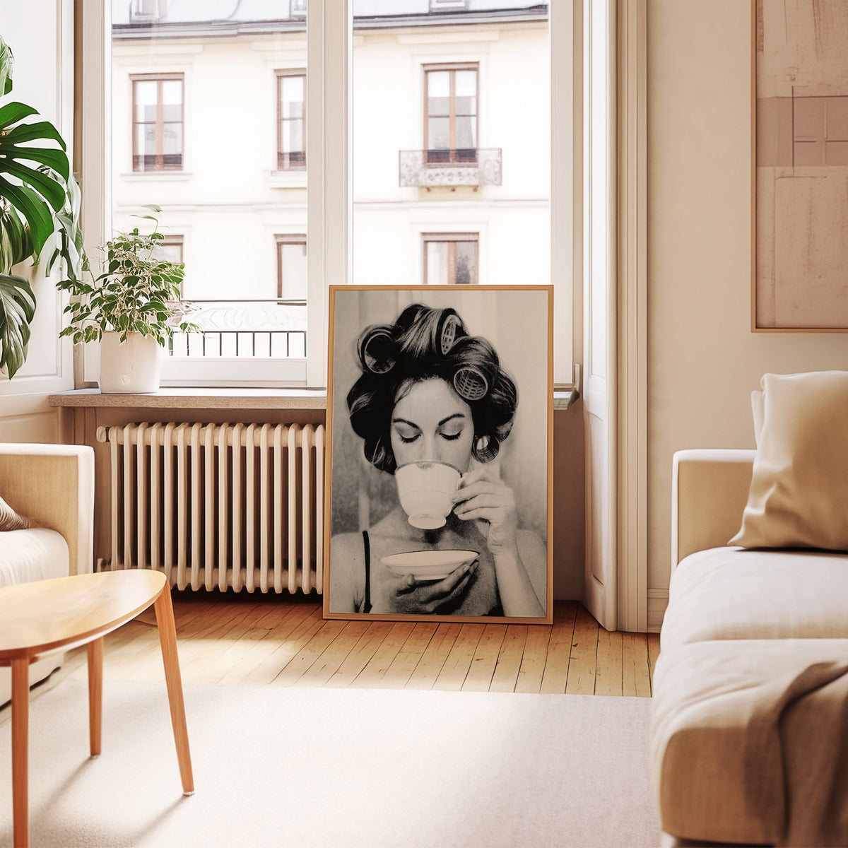 Woman in hair rollers sipping from a teacup print in an oak frame leaning by a French window in a living room