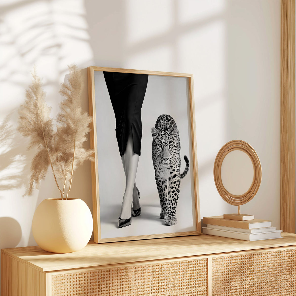 Woman's legs in heels walking beside leopard print in an oak frame on a rattan sideboard beside pampas grass