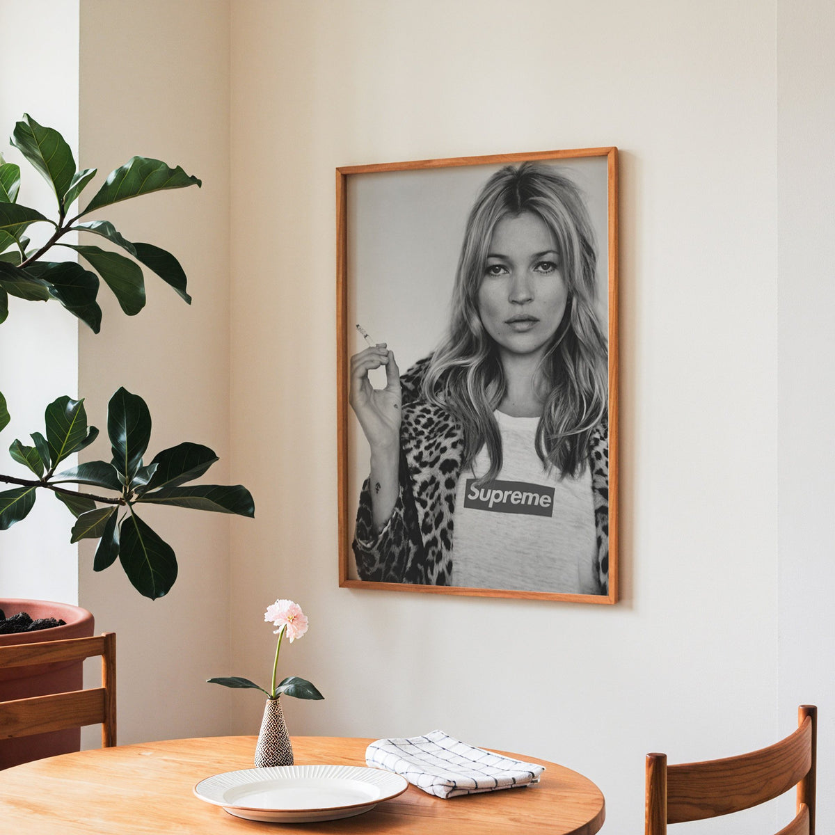 Woman in leopard coat holding a cigarette print in a teak frame above a round wooden dining table
