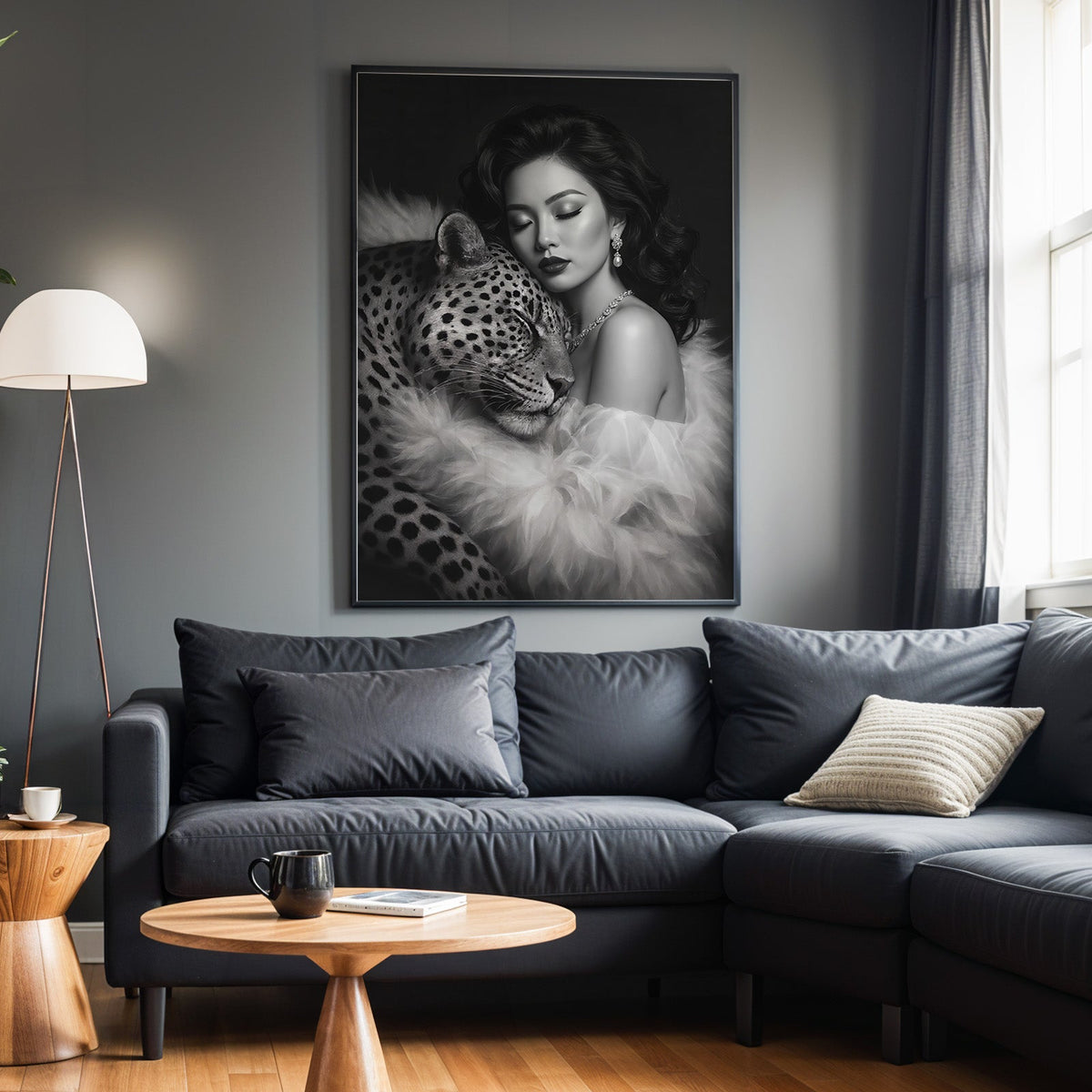 Woman leaning on leopard in fur black and white print in a black frame above a charcoal sofa on a grey wall