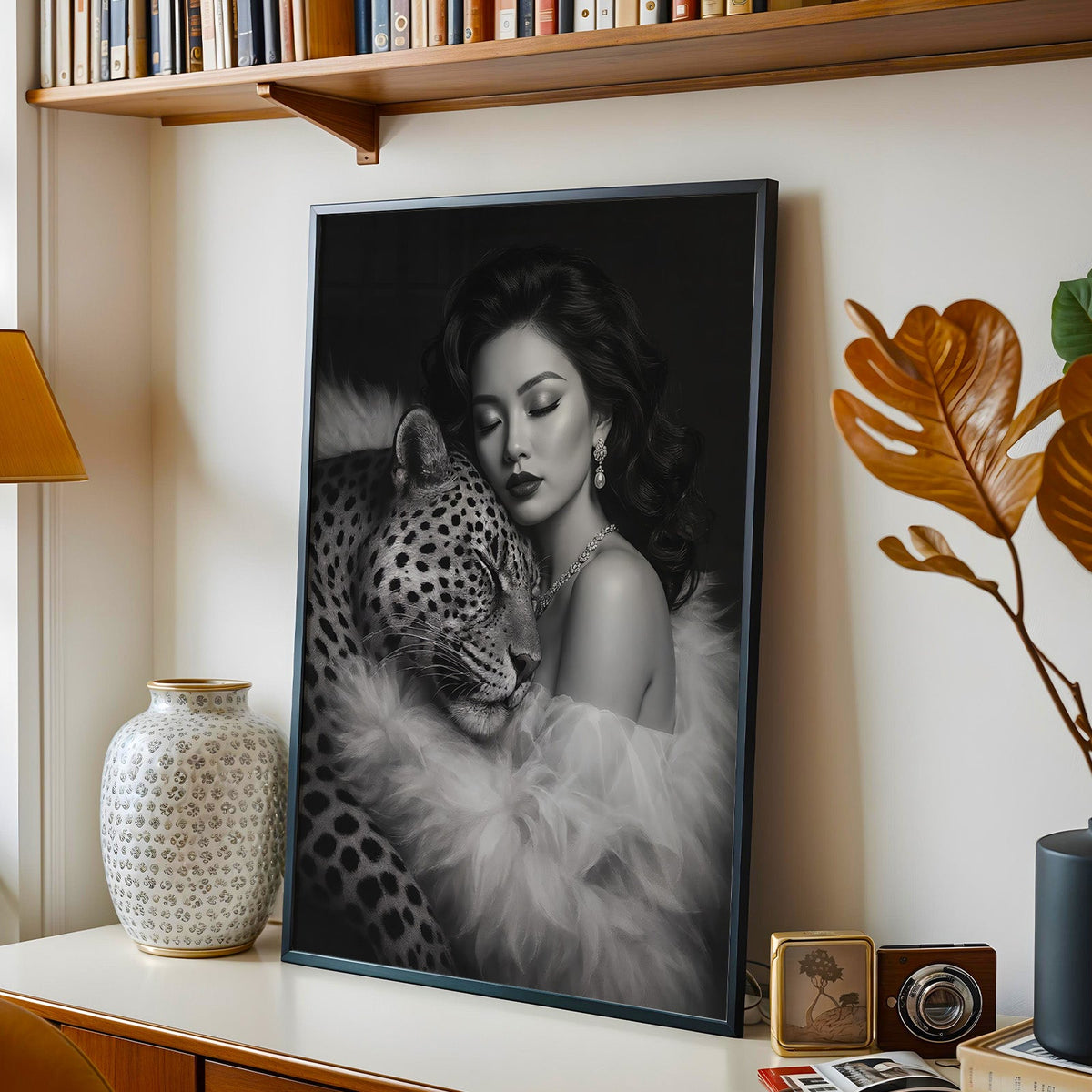 Woman leaning on leopard in fur black and white print in a black frame on a console under a bookshelf