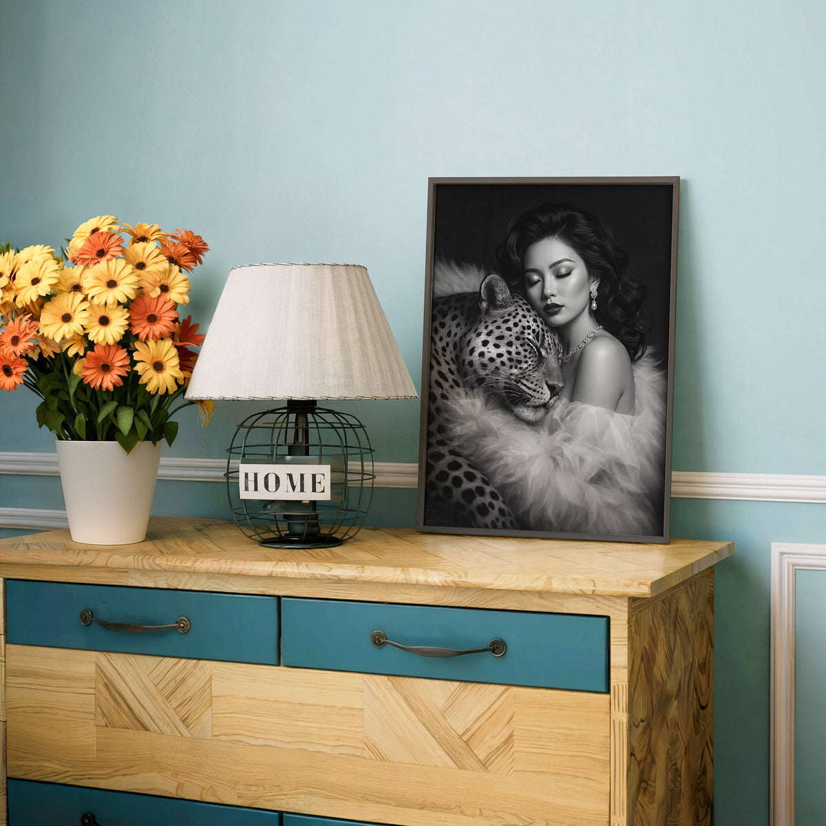 Woman leaning on leopard in fur black and white print in a charcoal frame on a teal dresser beside orange daisies