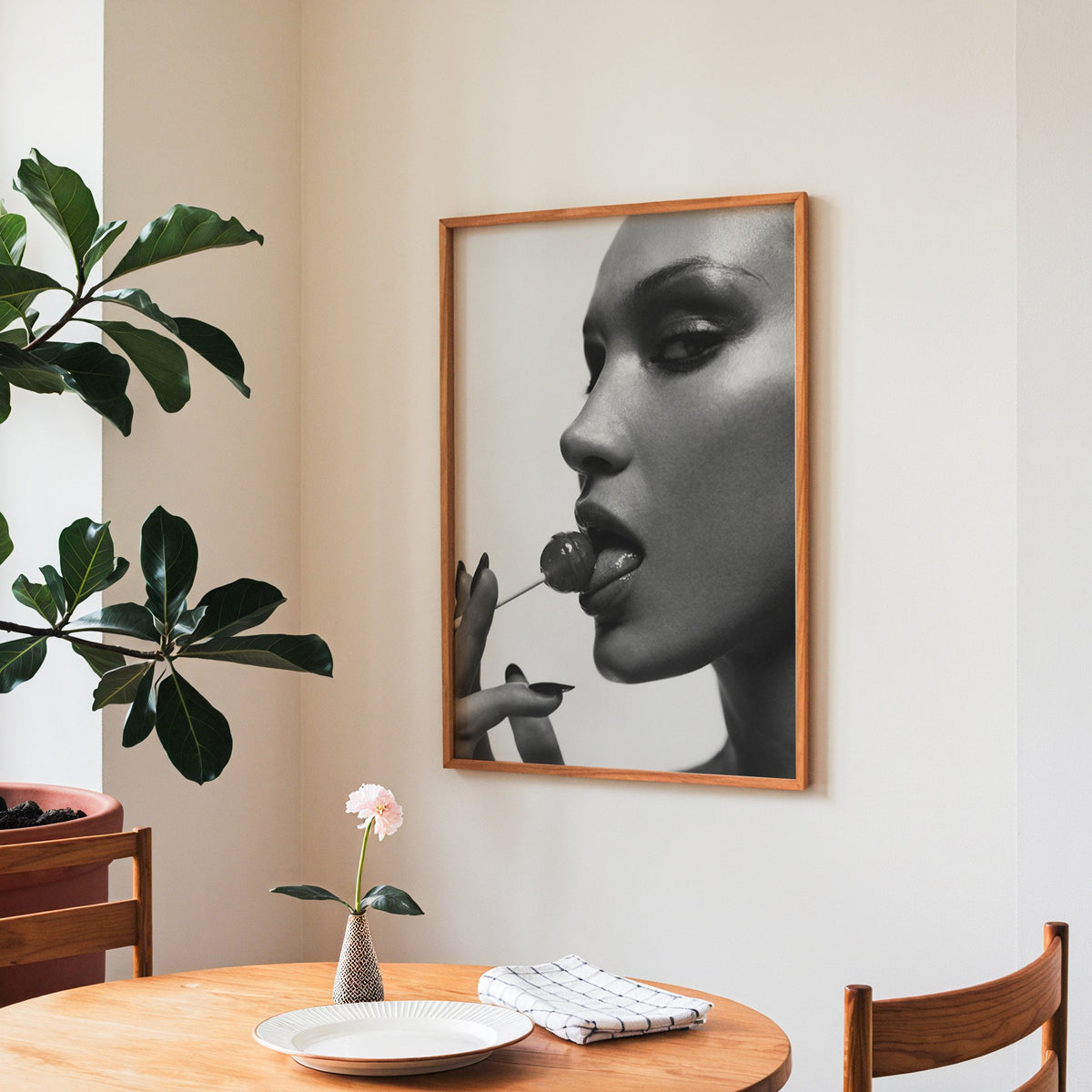 Glossy closeup with lollipop and black nails print in a teak frame above a round wooden dining table