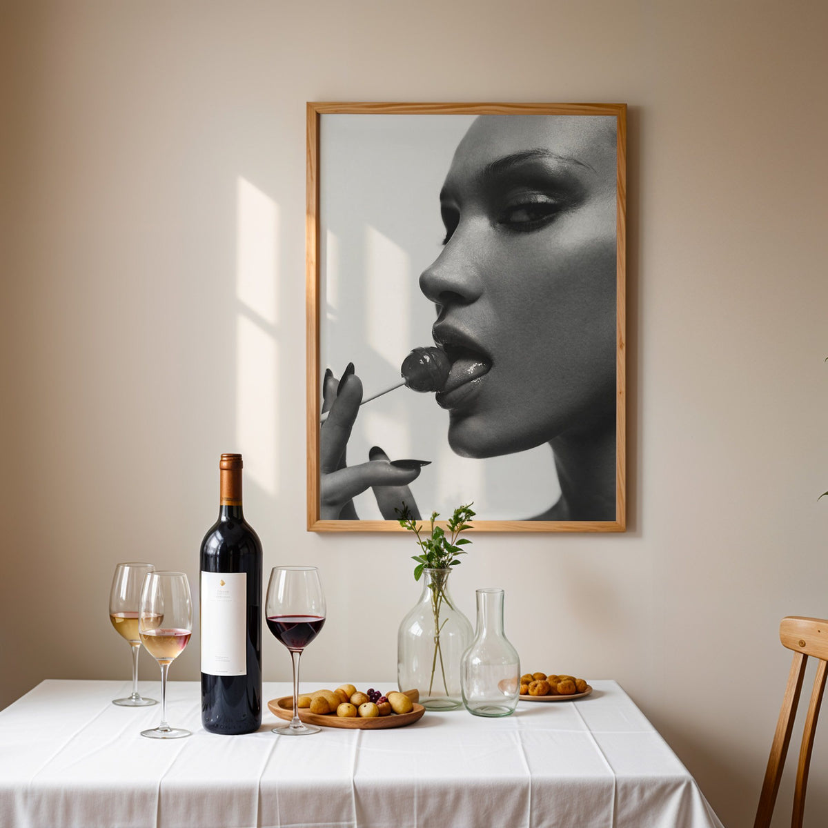 Glossy closeup with lollipop and black nails print in an oak frame above a table set with red wine and glasses