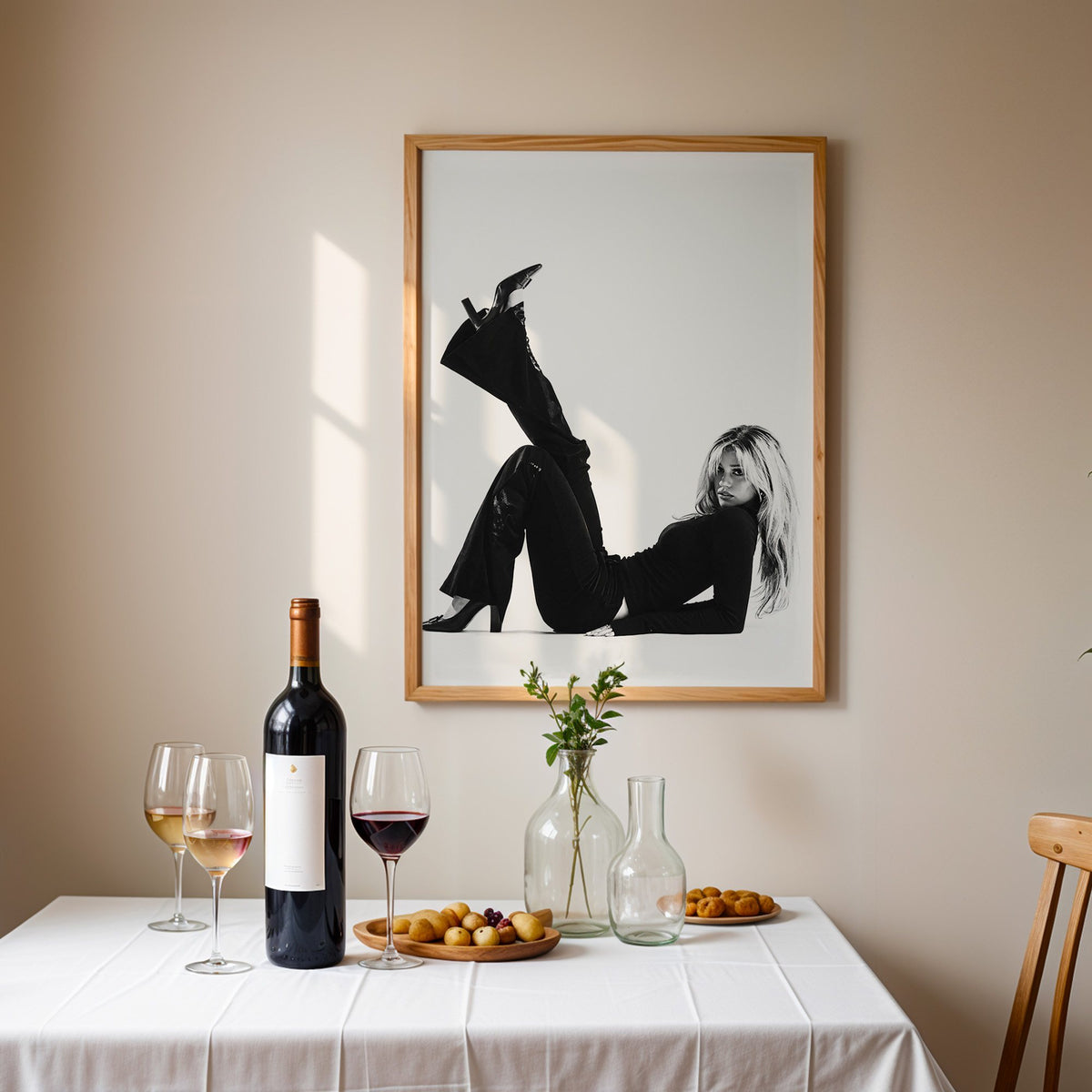 Woman in all black lying with leg raised print in an oak frame above a table set with red wine and glasses