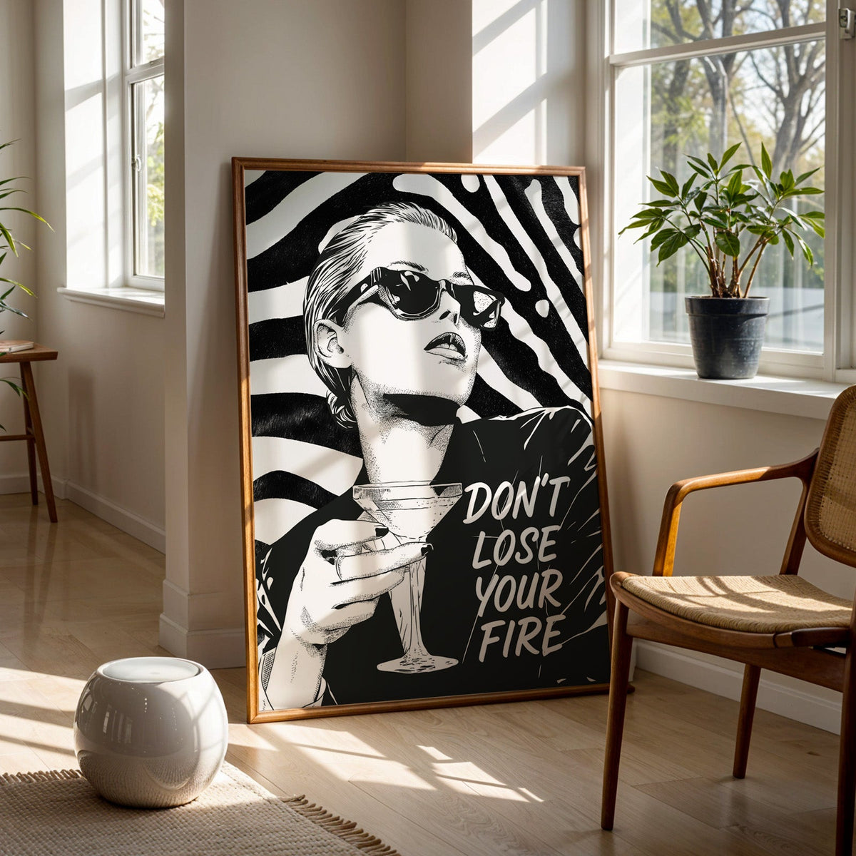 Woman with martini on zebra stripe backdrop ink print in a walnut frame on a wood floor beside a cane chair and sunny window