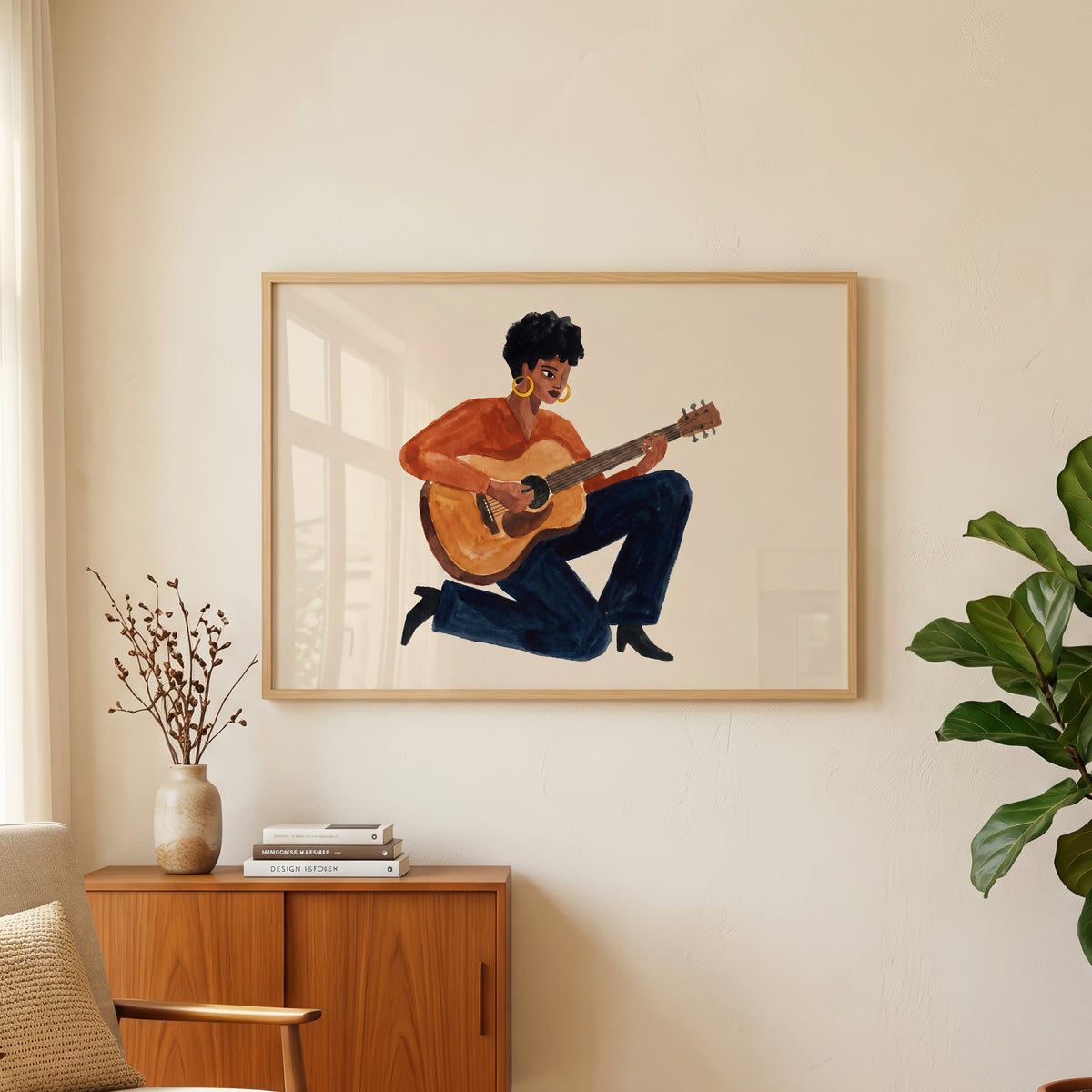 Watercolor guitarist print in an oak frame above a teak sideboard beside a fig tree
