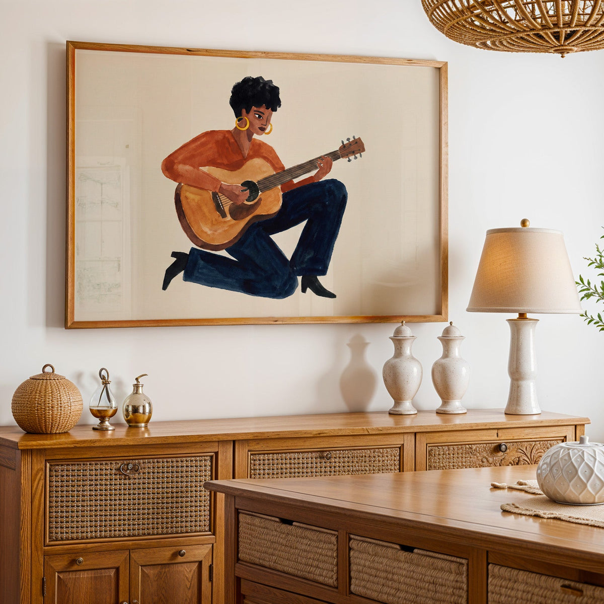 Acoustic guitar portrait print in an oak frame above a cane sideboard with a table lamp