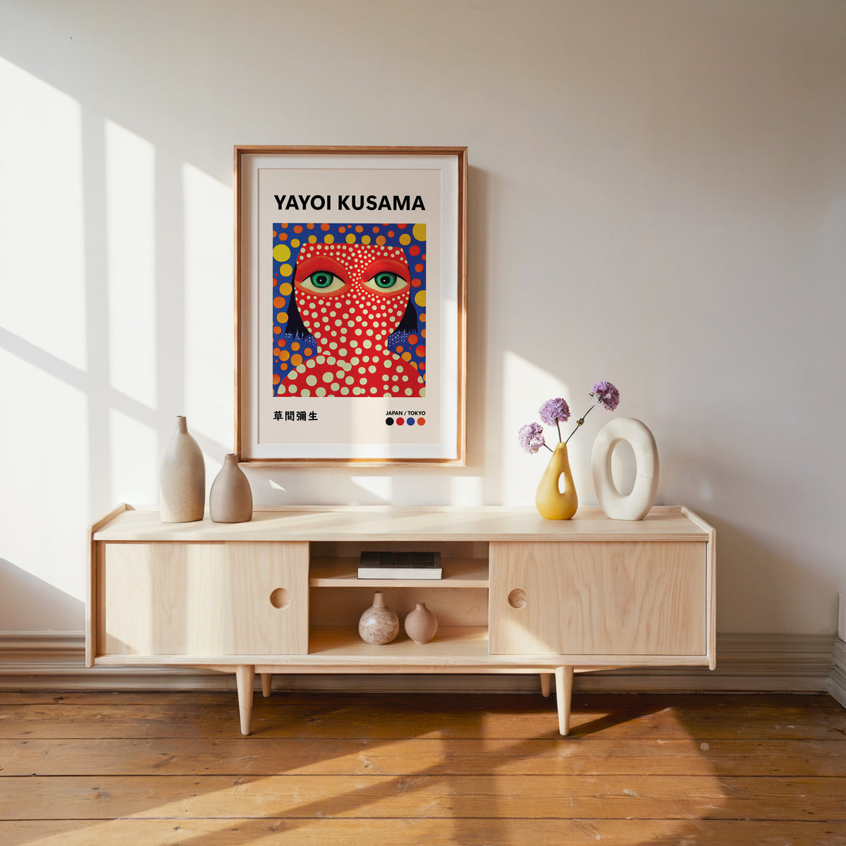 Yayoi Kusama inspired red face green eyes print above a pale wood console