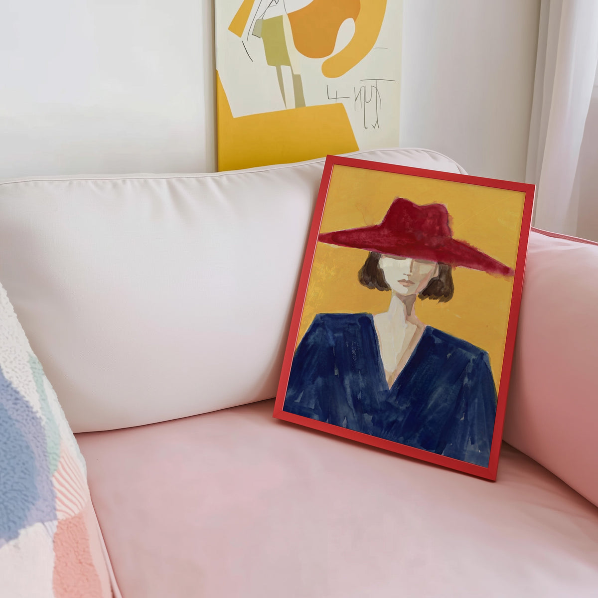 Woman in navy and red print shown in a red frame leaning on a blush pink sofa