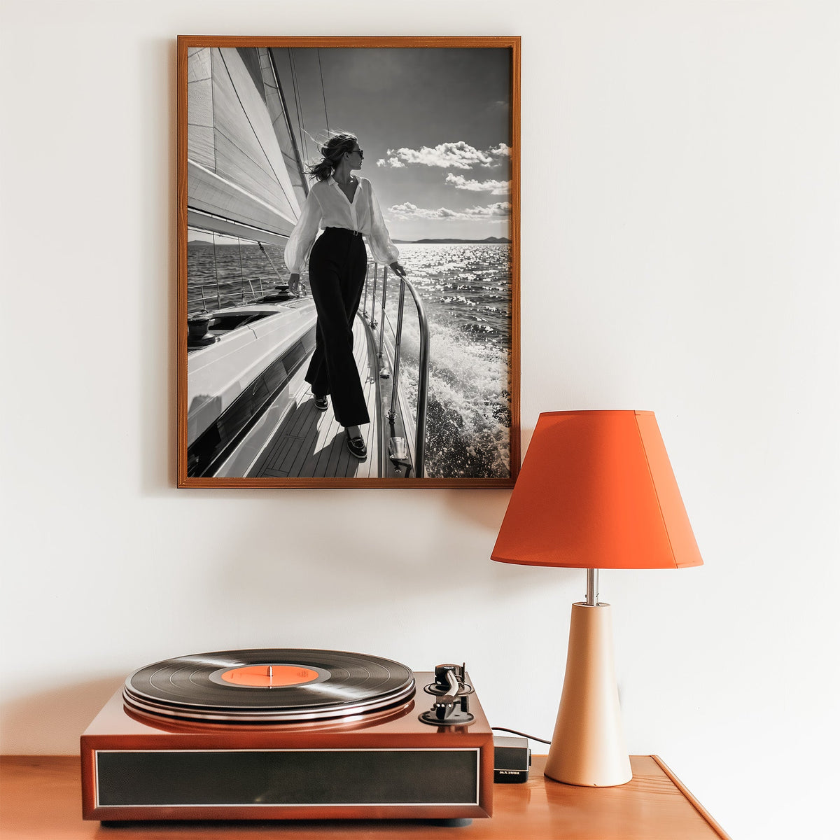 Woman in white blouse on a sailboat deck print in a walnut frame above a record player and orange lamp