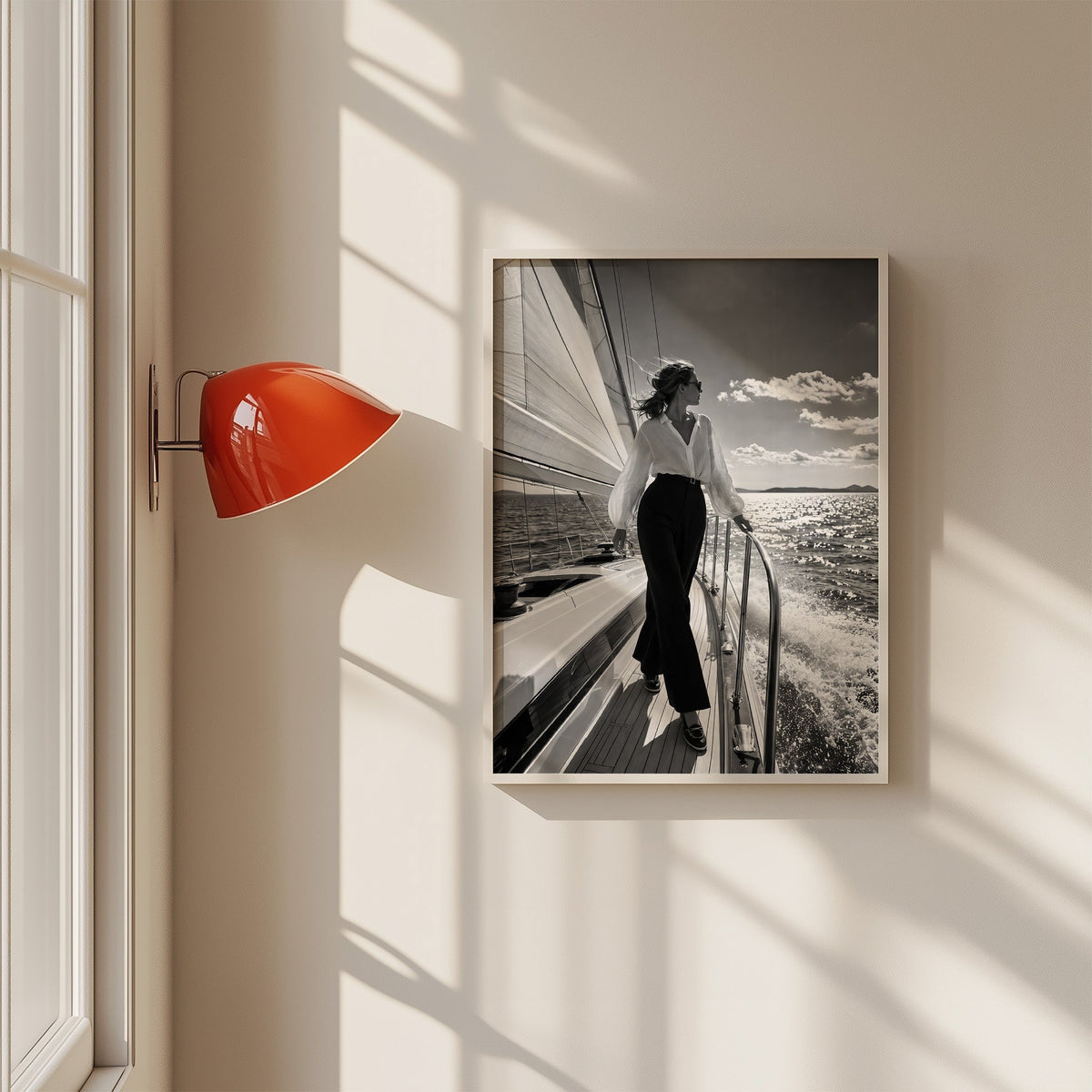 Woman in white blouse on a sailboat deck print in a white frame on a sunlit wall beside a red sconce