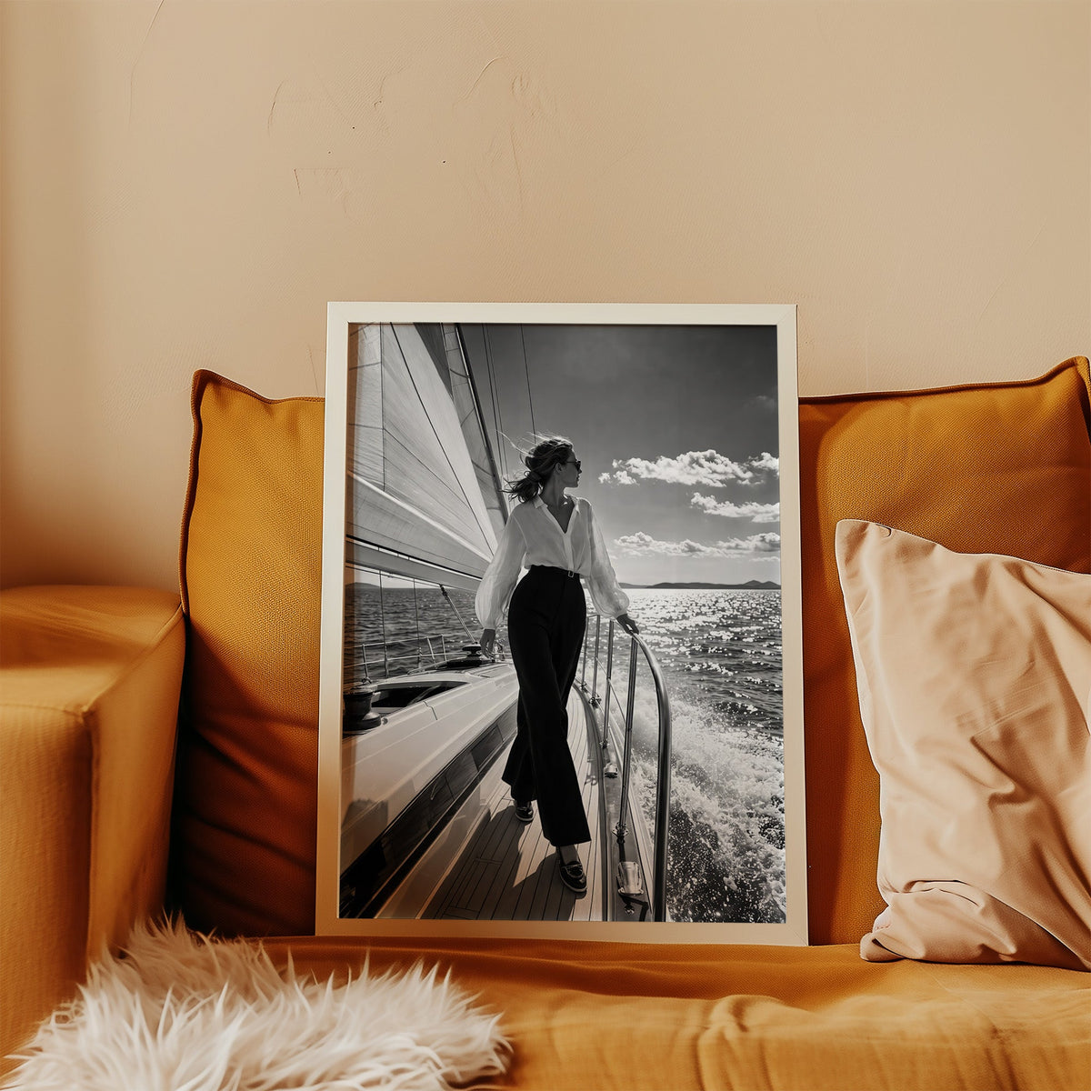 Woman in white blouse on a sailboat deck print in a white frame leaning on a mustard velvet sofa
