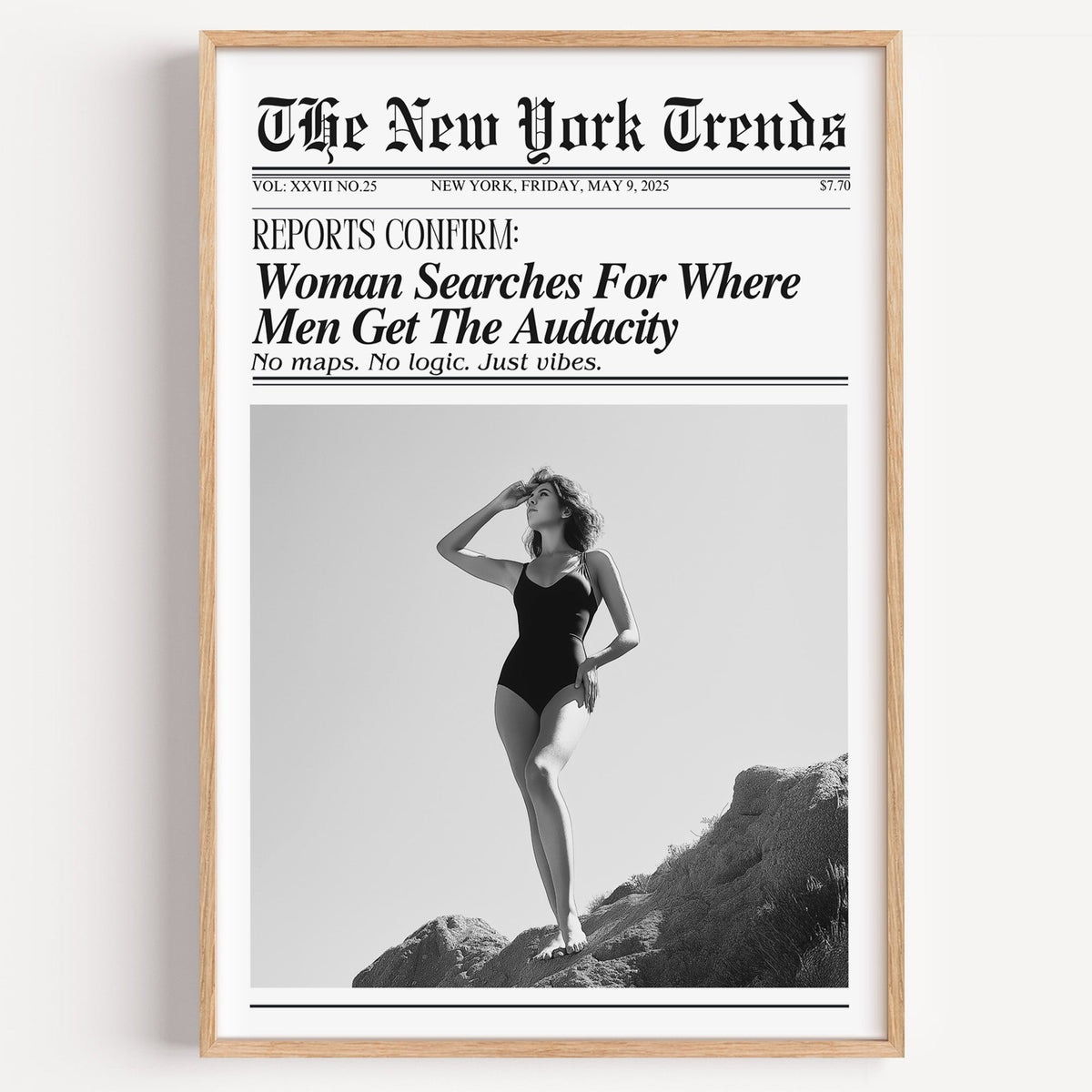 Woman on rocks shading her eyes mock newspaper print in a light oak frame on a plain white wall