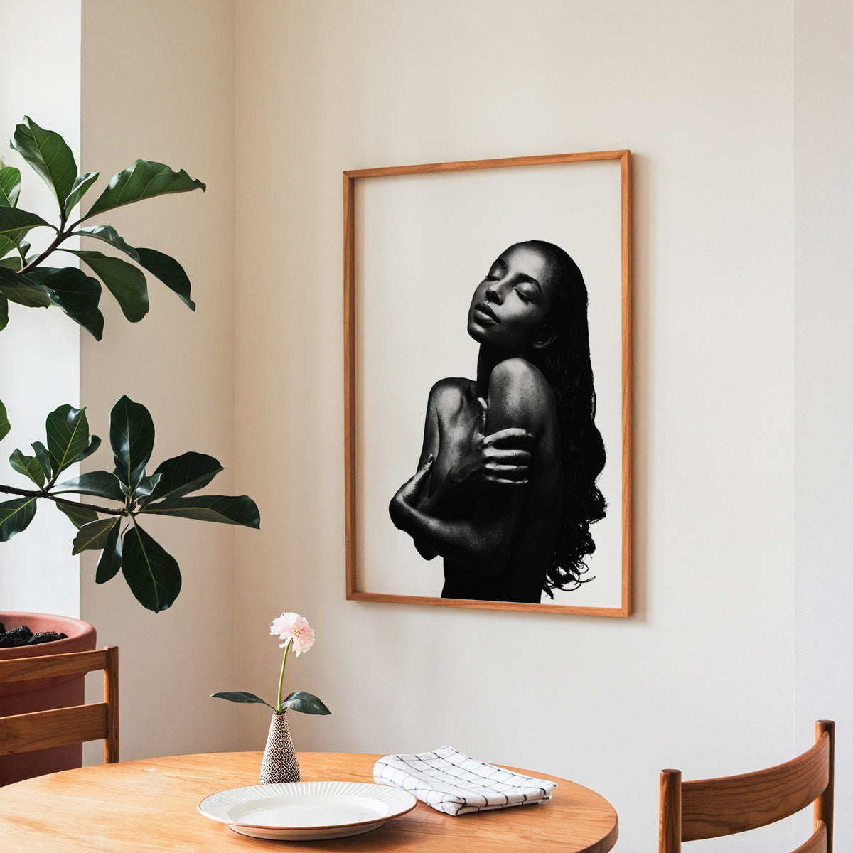 Backlit woman silhouette hugging her shoulders print in a teak frame above a round wooden dining table