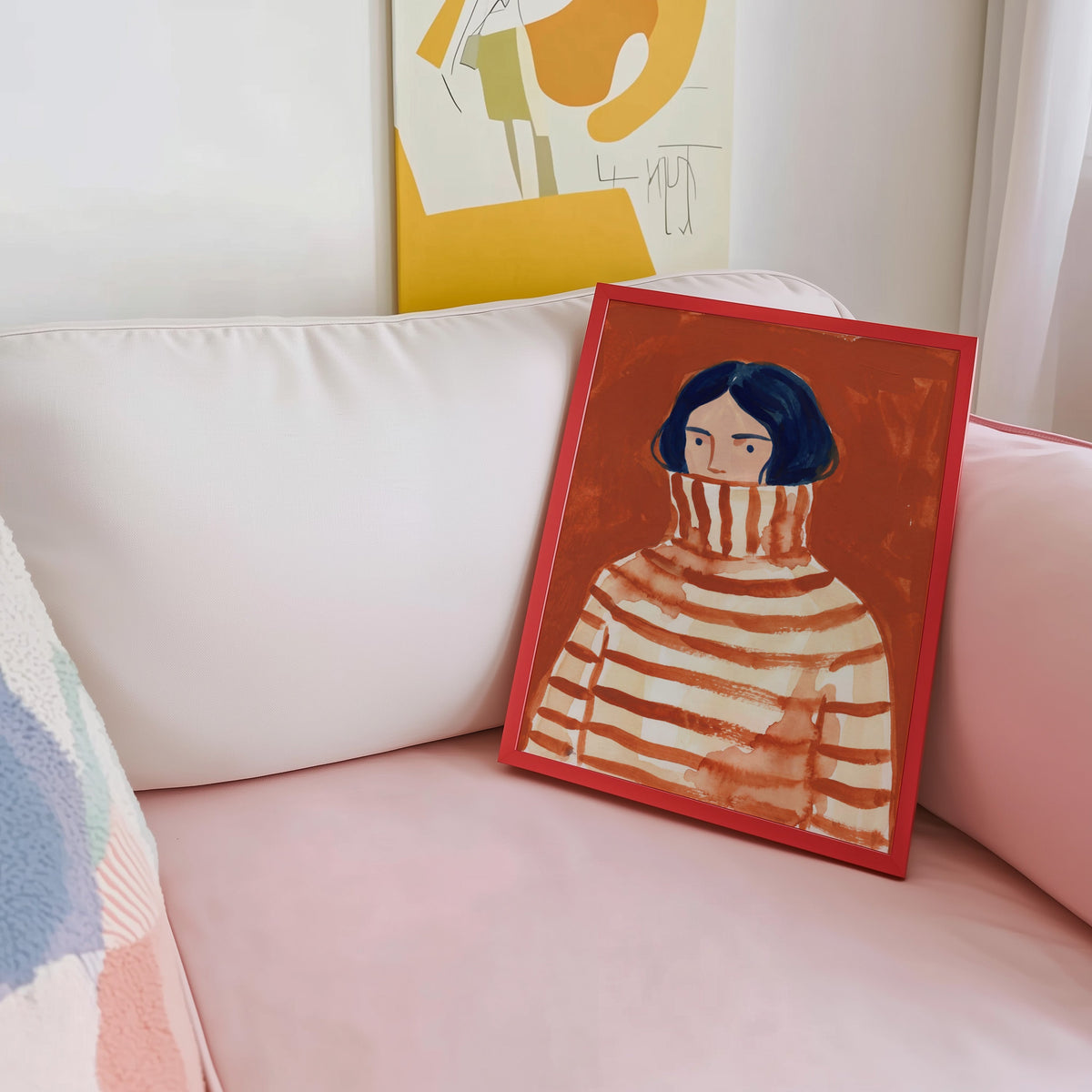 Watercolor woman portrait shown in a red frame leaning on a blush pink sofa