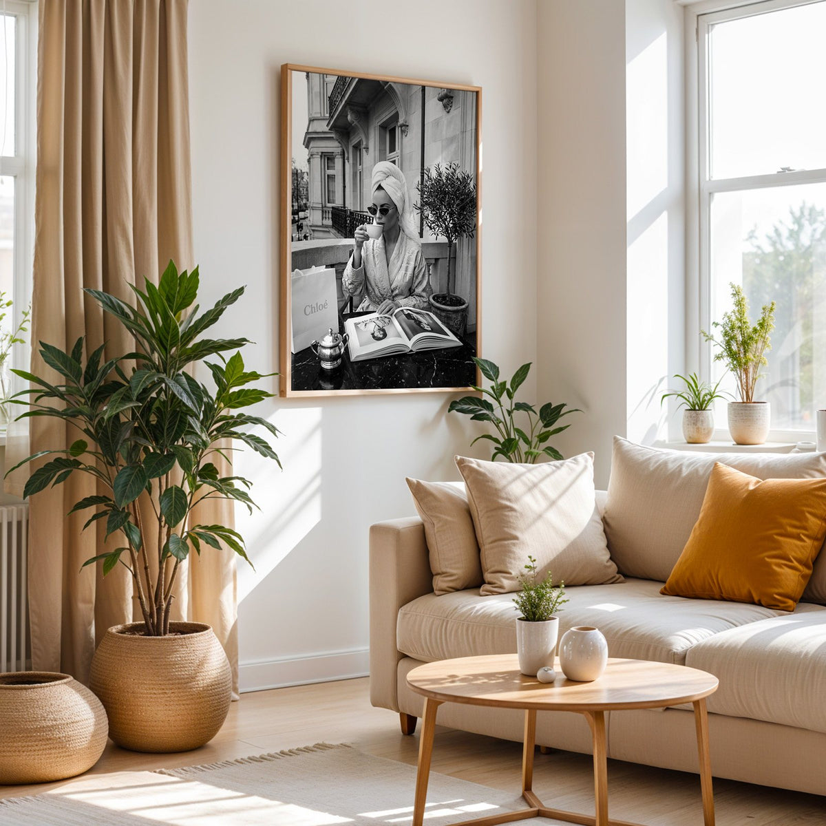 Woman in towel turban drinking coffee on balcony print in an oak frame above a cream sofa beside woven planters