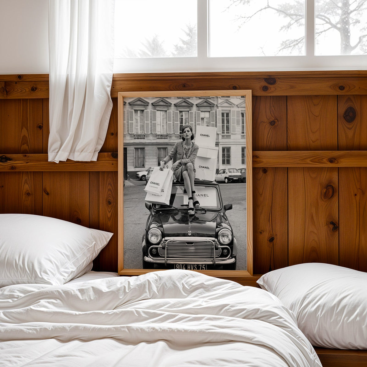 Woman in tweed suit on vintage mini car print in a pine frame leaning on a wood headboard over white bedding