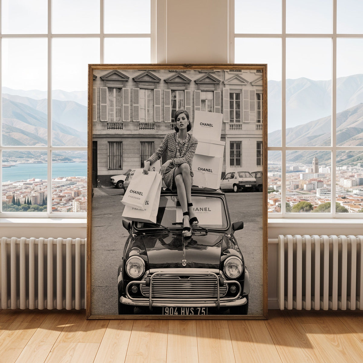 Woman in tweed suit on vintage mini car print shown in an antique gold frame by tall windows with a sea view