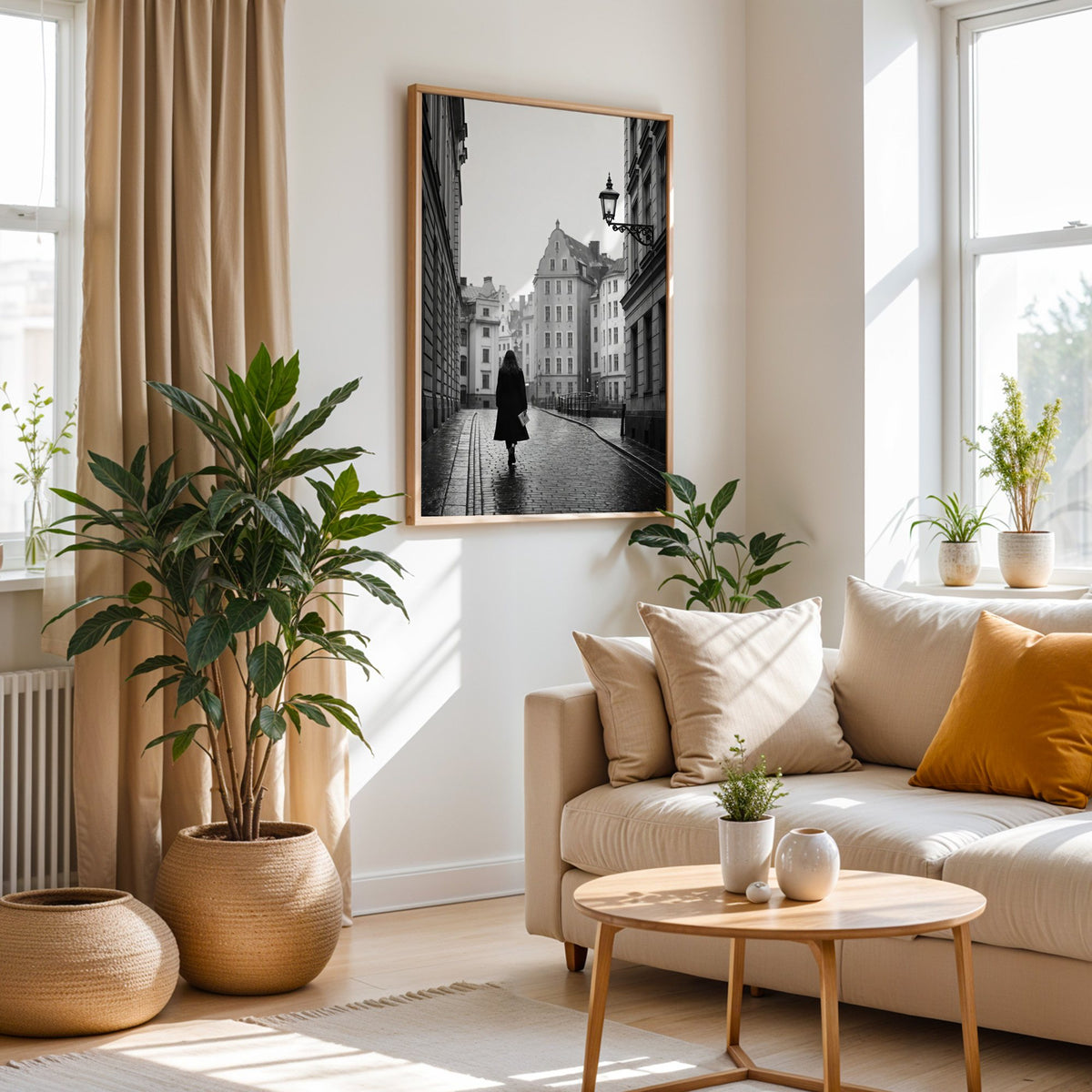 Woman walking on cobblestone old town street print in an oak frame above a cream sofa beside woven planters