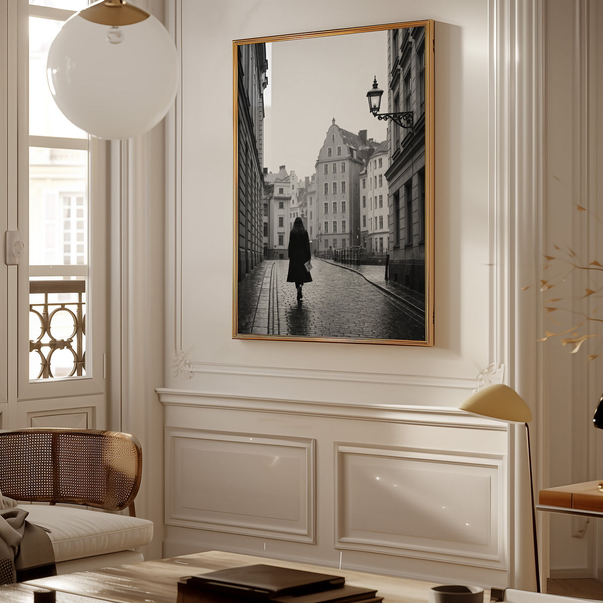 Woman walking on cobblestone old town street print shown in a gold frame in a Parisian paneled living room
