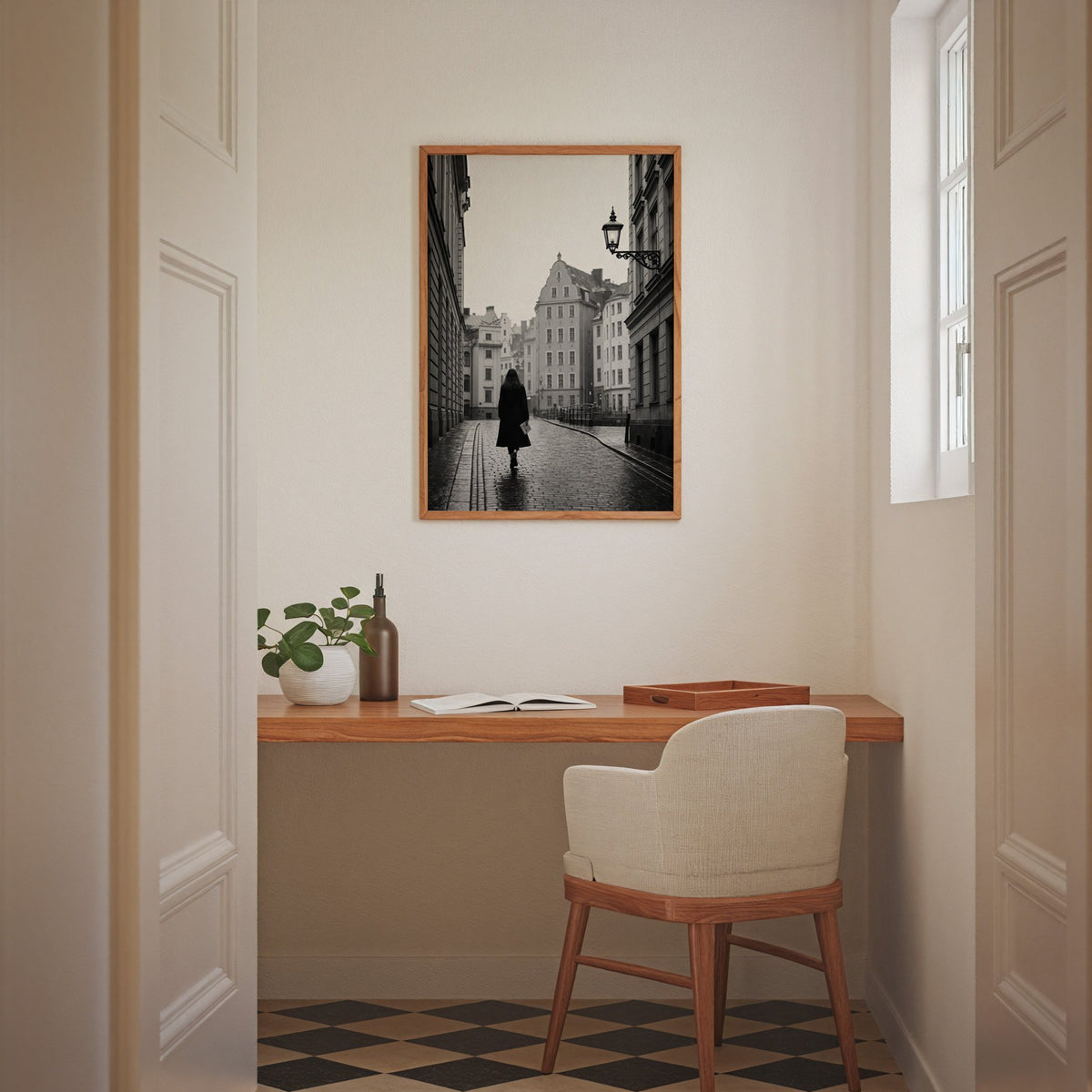 Woman walking on cobblestone old town street print in an oak frame above a home office desk nook