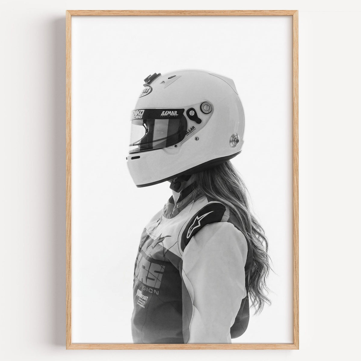 Woman in white racing helmet seen in profile print in a light oak frame on a plain white wall
