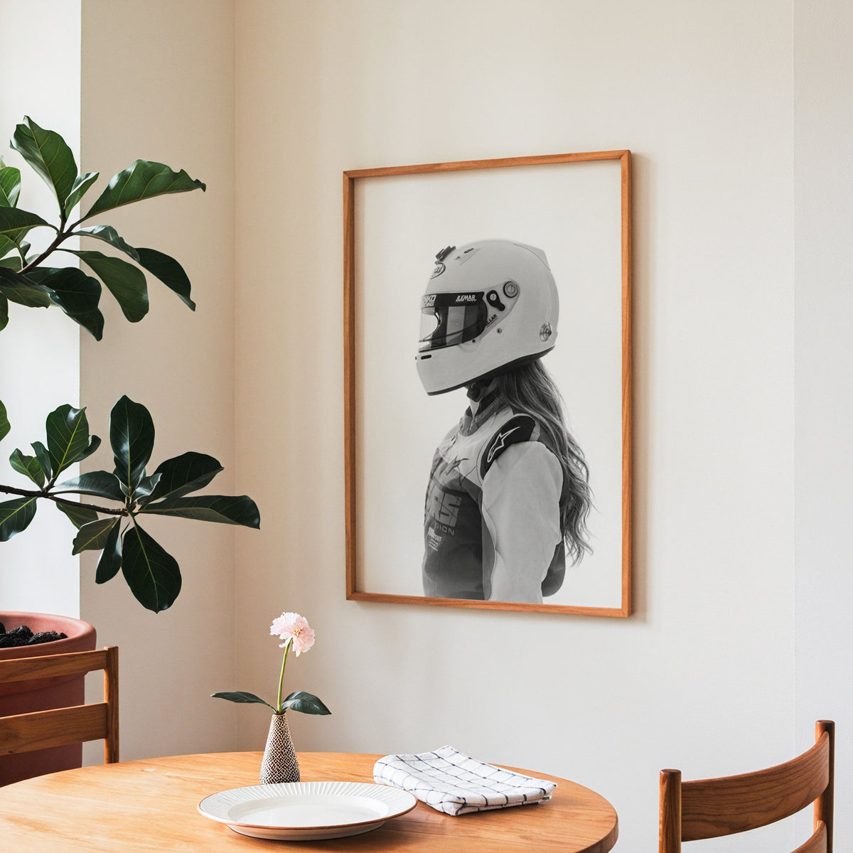Woman in white racing helmet seen in profile print in a teak frame above a round wooden dining table