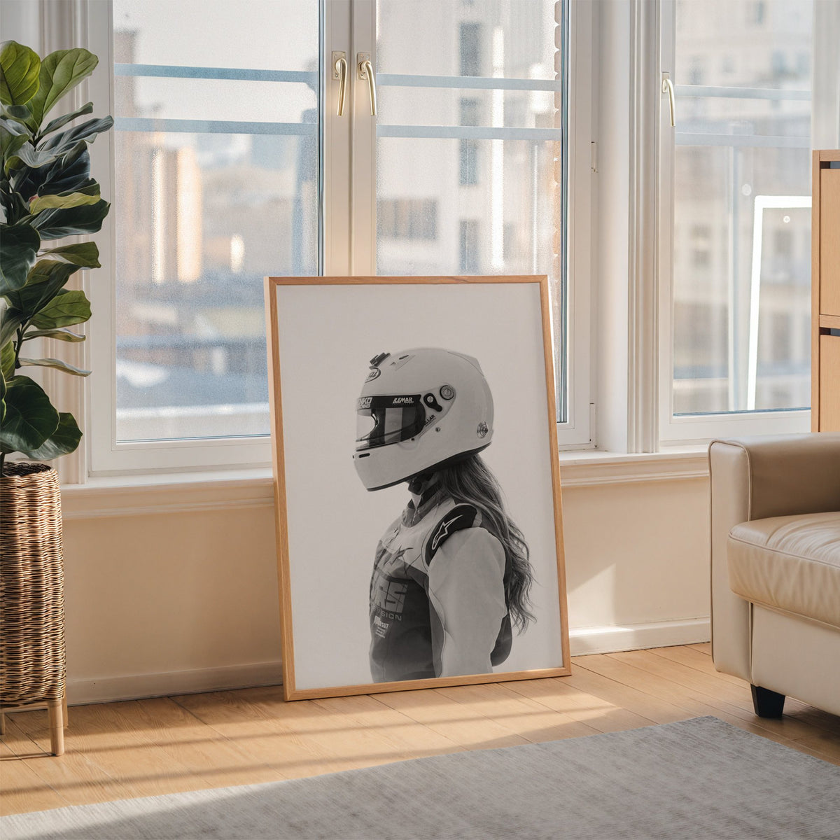 Woman in white racing helmet seen in profile print in an oak frame leaning on the floor beside a fiddle leaf fig