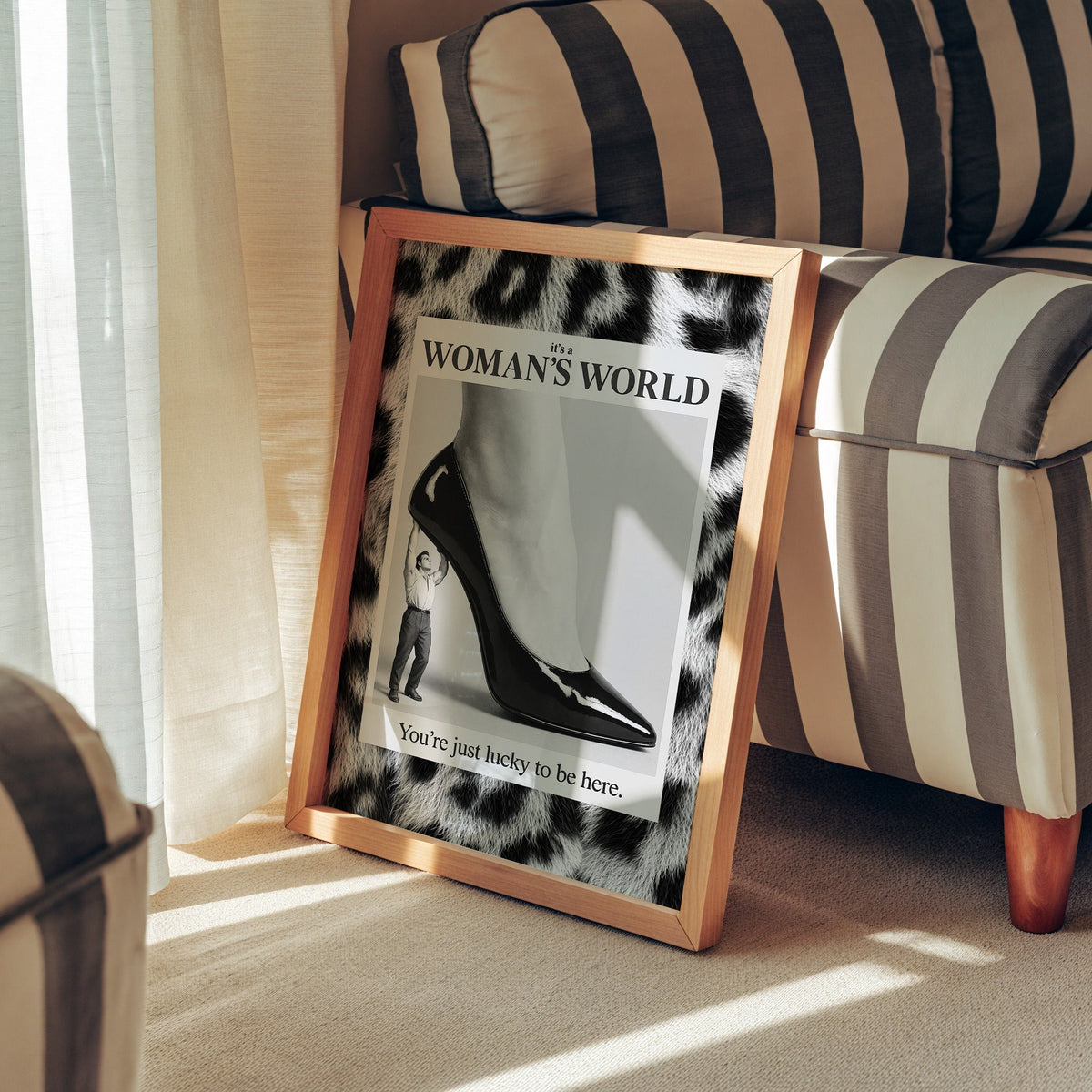 Tiny man lifting giant stiletto in leopard frame print in a pine frame leaning against a striped armchair