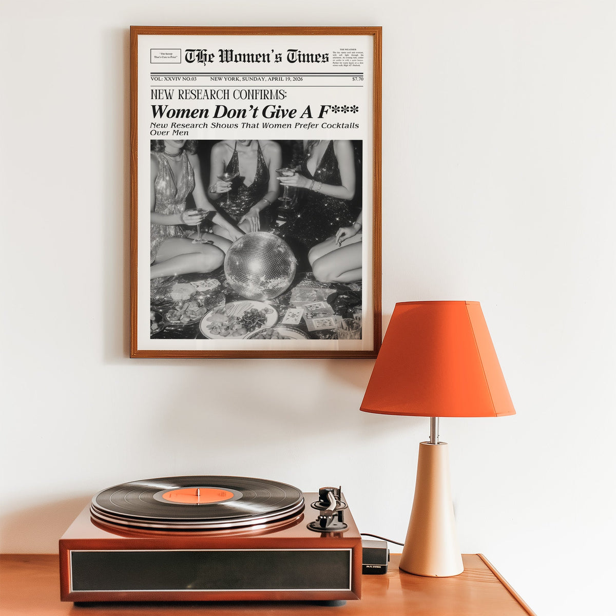 Mock front page with women around a disco ball print in a walnut frame above a record player and orange lamp